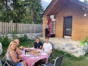 a group of people sitting at a table in a backyard at Bujtina Arturi in Valbonë