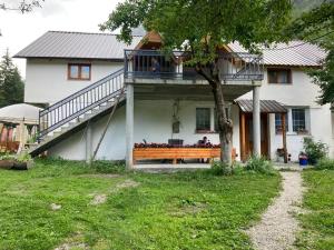 a house with a balcony and a wooden bench at Bujtina Arturi in Valbonë