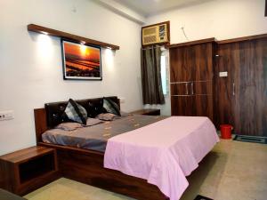 a bedroom with a large bed with a pink blanket at Khushi Paying Guest House in Varanasi