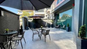 un patio con tavoli, sedie e ombrellone di Expo Hotel a Plovdiv