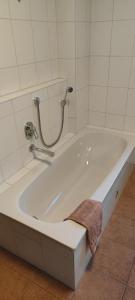 eine weiße Badewanne mit einem braunen Handtuch darauf in der Unterkunft Ferienwohnung zwischen Rhein und Schwarzwald in Bischweier