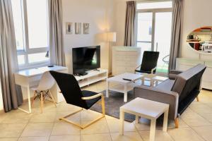 a living room with a couch and chairs and a tv at Unified Vacation Homes-Spacious Studio in lush green Motor City in Dubai