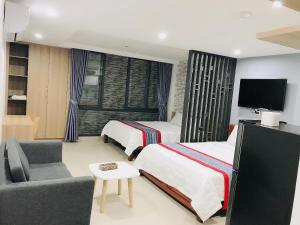 una camera con 2 letti, un divano e una TV di Hà Linh Apartment a Da Nang