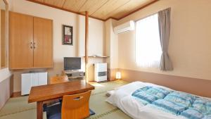sypialnia z biurkiem, łóżkiem, biurkiem i oknem w obiekcie Hotel Sato w mieście Shinhidaka