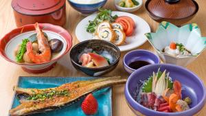 stół z talerzami żywności i miskami żywności w obiekcie Hotel Sato w mieście Shinhidaka
