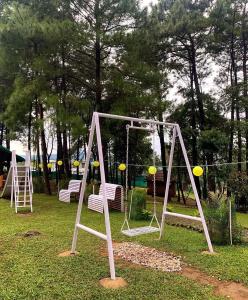 a swing set in a park with two chairs at Odyssey Stays Umbir, Umiam Lake in Mawlyngkhung