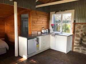 una cucina con armadi bianchi, lavandino e finestra di Black Range Erin Cottage, Tumbarumba a Tumbarumba