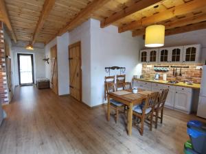a kitchen and dining room with a wooden table and chairs at Zabytkowy dom z 2 sypialniami i 2 ogródkami in Wydminy