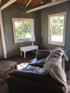 un soggiorno con divano e 2 finestre di Black Range Erin Cottage, Tumbarumba a Tumbarumba
