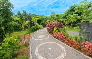 a walkway in a garden with flowers and trees at DARZA LUXURY RESORTs in Coimbatore
