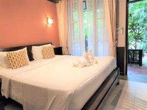 a white teddy bear sitting on a bed in a bedroom at Samed Villa Resort in Ko Samed