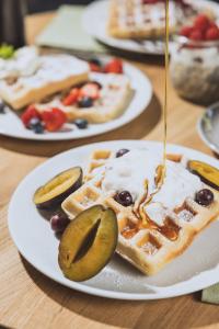 einen Teller mit Waffeln mit Sirup, Gurken und Früchten in der Unterkunft DAS GERLOS - Boutique Hotel in Gerlos