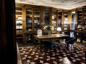a library with a table and chairs and bookshelves at Palazzo Cappuccini Art Relais in Naples