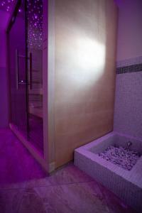 a bathroom with a shower and a tub with purple lights at La Portineria Luxury B&B in Piancogno