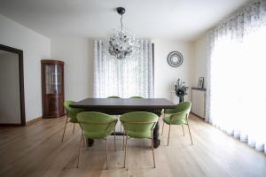 uma sala de jantar com uma mesa preta e cadeiras verdes em La Portineria Luxury B&B em Piancogno