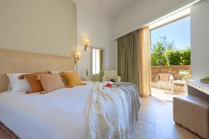 a bedroom with a large white bed and a balcony at Giannoulis – Santa Marina Beach Hotel in Agia Marina Nea Kydonias