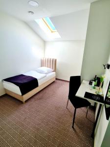 ein Schlafzimmer mit einem Bett, einem Tisch und einem Stuhl in der Unterkunft Via Hotel Polkowice in Polkowice