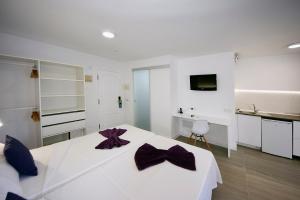 a white bedroom with a large white bed with purple bows at Skyview Hotel Tenerife in Puerto de la Cruz