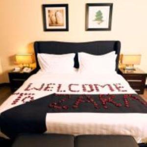 a bed with a black and white blanket and two lamps at Zara Continental Hotel in Al Khobar