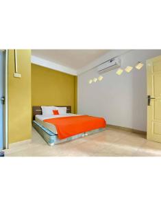 a bedroom with a bed with an orange blanket at KoolKost Syariah near Stasiun Tanjung Karang Lampung in Bandar Lampung
