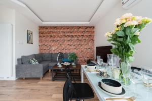 a living room with a couch and a table with flowers at Avenue Apartment by LoftAffair in Kraków