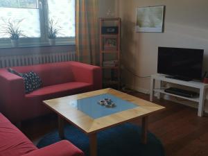 Sala de estar con sofá rojo y mesa de centro en Gemütliche Gästewohnung in ruhiger Lage en Kronshagen