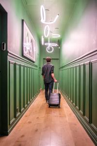 mężczyzna idący korytarzem z walizką w obiekcie Joro Living w Paryżu