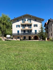 a large white building with a large grass field at Casa Dalsass - Appartamenti nel verde in Cavedago +96 photos