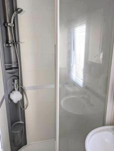 ein Bad mit einer Dusche, einem WC und einem Waschbecken in der Unterkunft Immaculate Sen friendly 3-Bed caravan in Porthcawl in Porthcawl