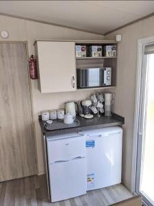 een kleine keuken met een fornuis en een magnetron bij Immaculate Sen friendly 3-Bed caravan in Porthcawl in Porthcawl