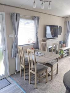 ein Esszimmer mit einem Holztisch und Stühlen in der Unterkunft Immaculate Sen friendly 3-Bed caravan in Porthcawl in Porthcawl