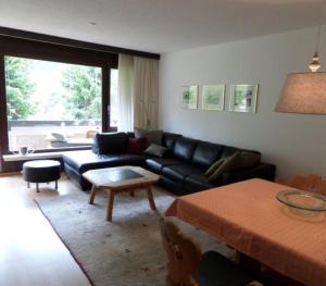 a living room with a black couch and a table at Carlton am Golf C14 in Davos