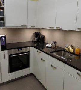 a kitchen with white cabinets and a sink at Carlton am Golf C14 in Davos +2 photos
