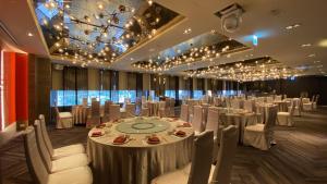 un salón de banquetes con mesas y sillas blancas y lámparas de araña en Monarch Plaza Hotel en Taoyuan