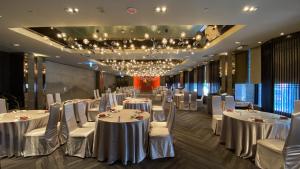 un salón de banquetes con mesas blancas y sillas blancas en Monarch Plaza Hotel en Taoyuan