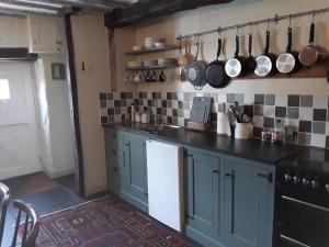 una cocina con armarios azules, ollas y sartenes en la pared en 6 Bridge St., en Brecon