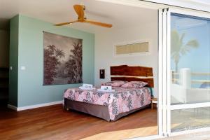 a bedroom with a bed and a ceiling fan at Villa Pirogue, pieds dans l'eau in Étang-Salé