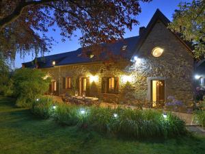 una casa de piedra con luces en el patio por la noche en Le Clos du Piheux en Thorigné-dʼAnjou