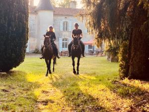 Chateau La Rochette في Lisle: شخصان يركبان الخيل أمام المنزل