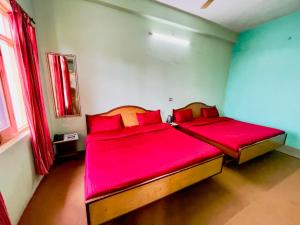 two beds in a room with red sheets at Grand view lodge and Restaurant Dharamshala - Partial Prepayment required to confirm booking in Dharamshala