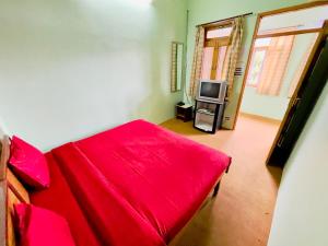 a bedroom with a red bed and a television at Grand view lodge and Restaurant Dharamshala - Partial Prepayment required to confirm booking in Dharamshala