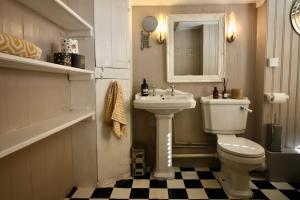 a bathroom with a sink and a toilet and a mirror at The Cottage at Barkwith House in Leiston