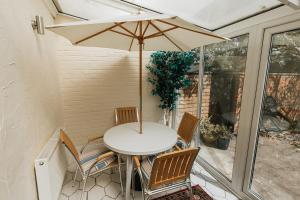 a table and chairs with an umbrella on a patio at WILLOW COTTAGE - Cost 3 Bed Cottage in Penrhyn Bay with Sea Views with Access to Snowdonia in Llandrillo-yn-Rhôs