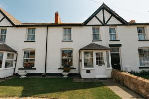 a white house with a white door and windows at WILLOW COTTAGE - Cost 3 Bed Cottage in Penrhyn Bay with Sea Views with Access to Snowdonia in Llandrillo-yn-Rhôs