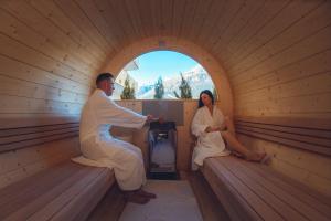 een man en vrouw zittend in een sauna bij Hotel La Perla in Andalo