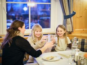 Eine Gruppe von drei Mädchen, die an einem Tisch sitzen und Wein trinken. in der Unterkunft Hotel Kirchboden by Alpeffect Hotels in Wagrain