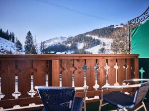 two chairs on a deck with a snowy mountain at Hotel Kirchboden by Alpeffect Hotels in Wagrain