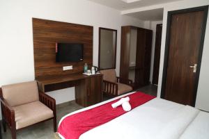 Schlafzimmer mit einem Bett, einem Schreibtisch und einem TV in der Unterkunft Hotel Cordelia inn in Rishikesh
