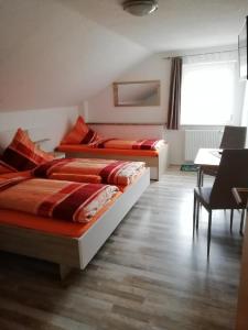 two beds in a room with a table and chairs at Pension Fohlenhof in Frauenau