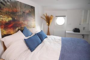 una camera da letto con un letto con cuscini blu e un dipinto di Hotel Restaurant Brasserie Feestzaal Ahoi, Kortrijk a Courtrai